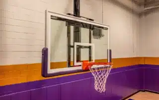 A basketball player dunking on a glass backboard hoop outdoors
