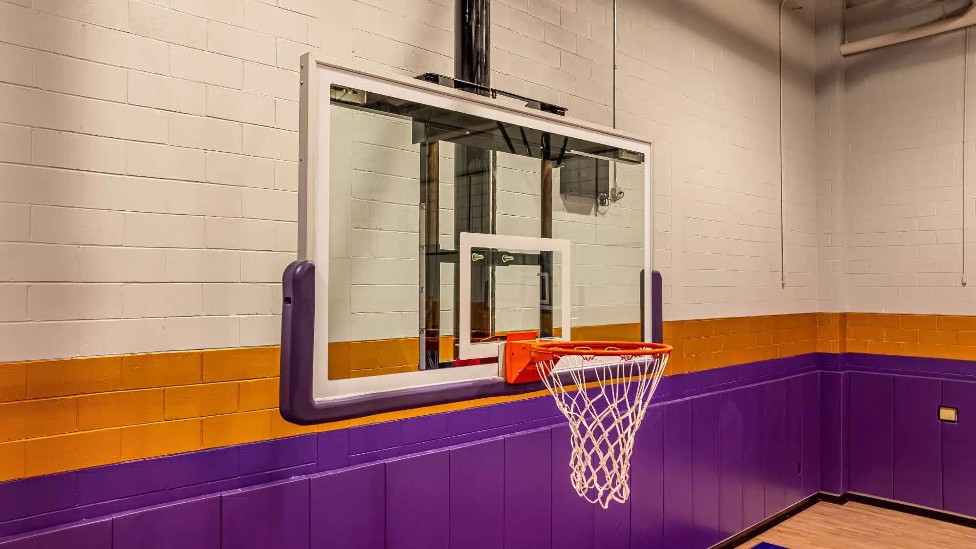A basketball player dunking on a glass backboard hoop outdoors