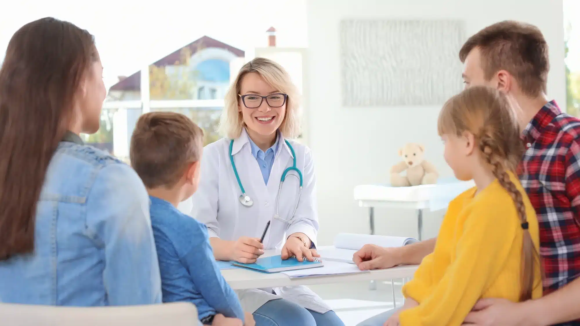 A doctor smiling with a happy family in the background