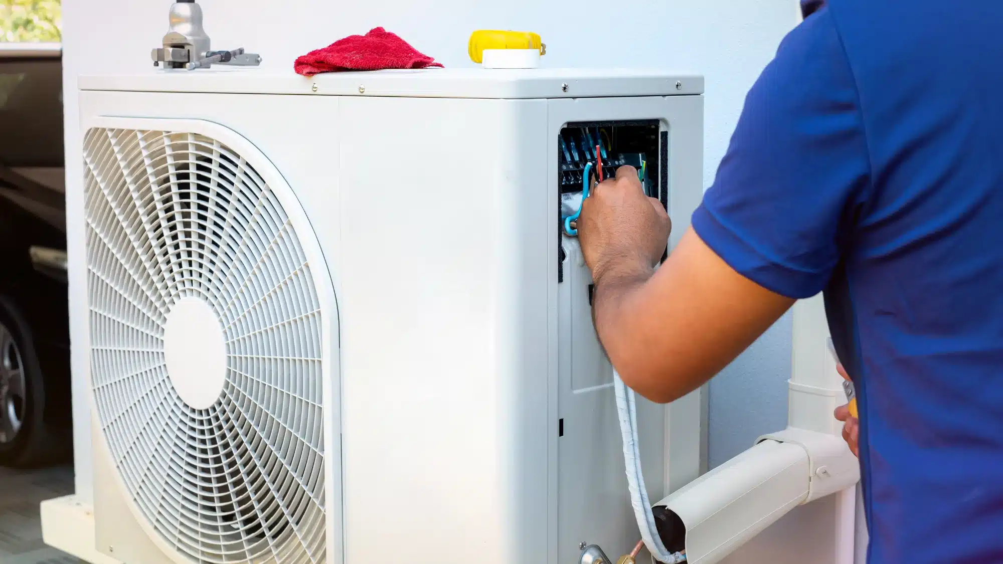 A professional HVAC technician inspects a clean, efficient heat pump system outside a modern home.