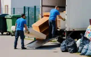 Professional movers carefully loading a sofa onto a truck in a Briarcliff Manor neighborhood.