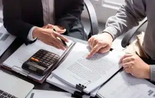 Business buyer reviewing contracts and financial documents with an advisor while exploring acquisition loans to finance a franchise purchase.