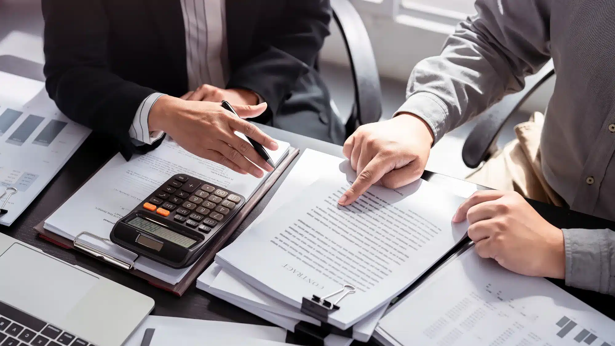 Business buyer reviewing contracts and financial documents with an advisor while exploring acquisition loans to finance a franchise purchase.