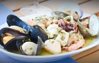 Plate of assorted fresh seafood including mussels, clams, shrimp, and fish